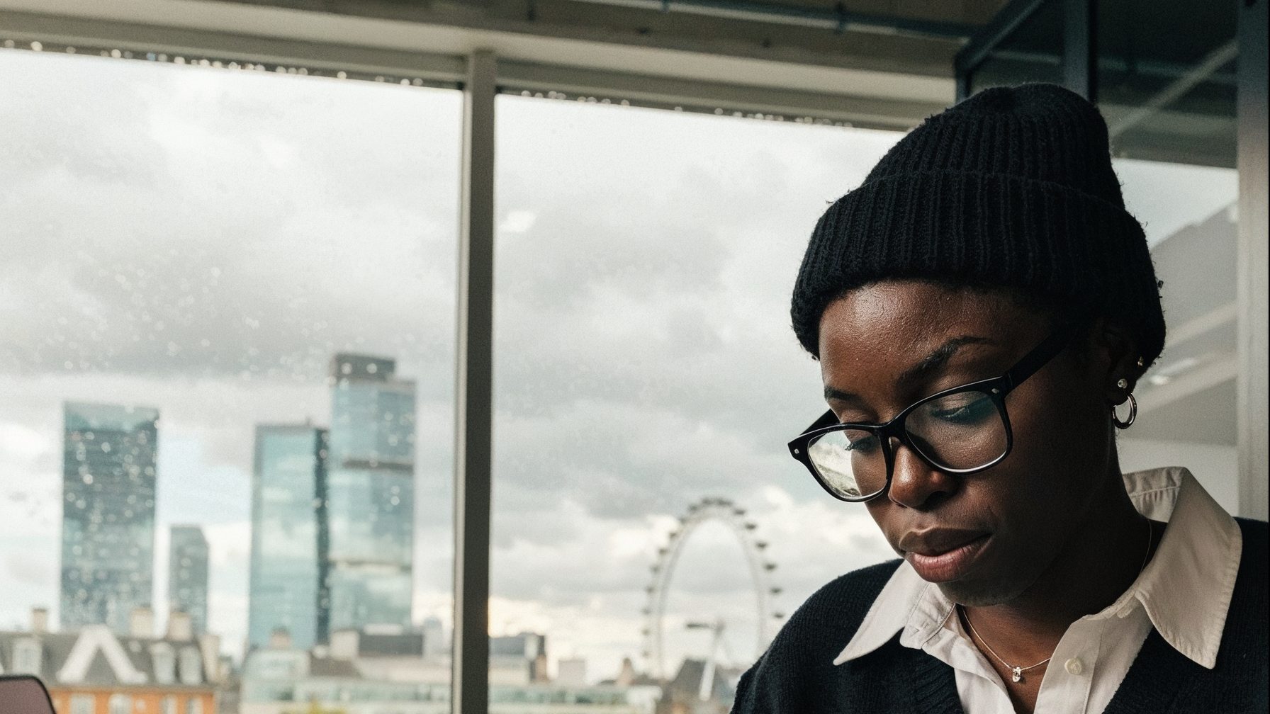 A strategist beside a London window, looking down at work just out of frame